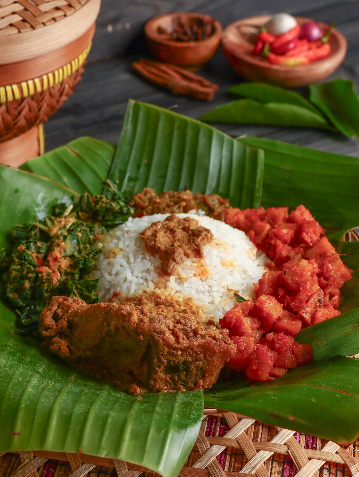 Nasi putih dengan rendang, sambal, dan sayur di atas daun pisang